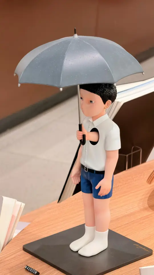 A figurine of a boy holding an umbrella