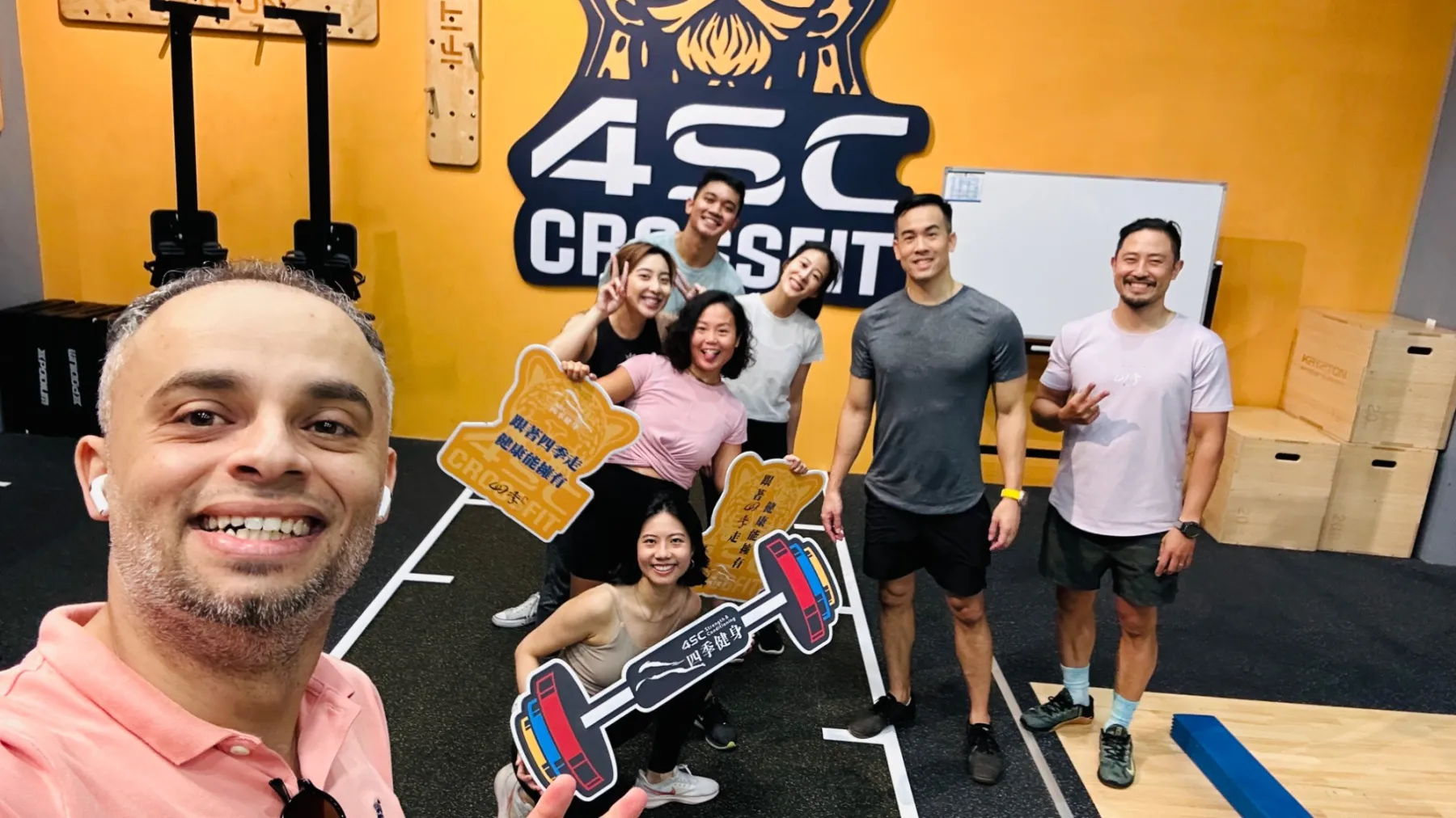Alhasan taking a selfie with a class at 4SC CrossFit, everyone smiling, holding cut-out signs